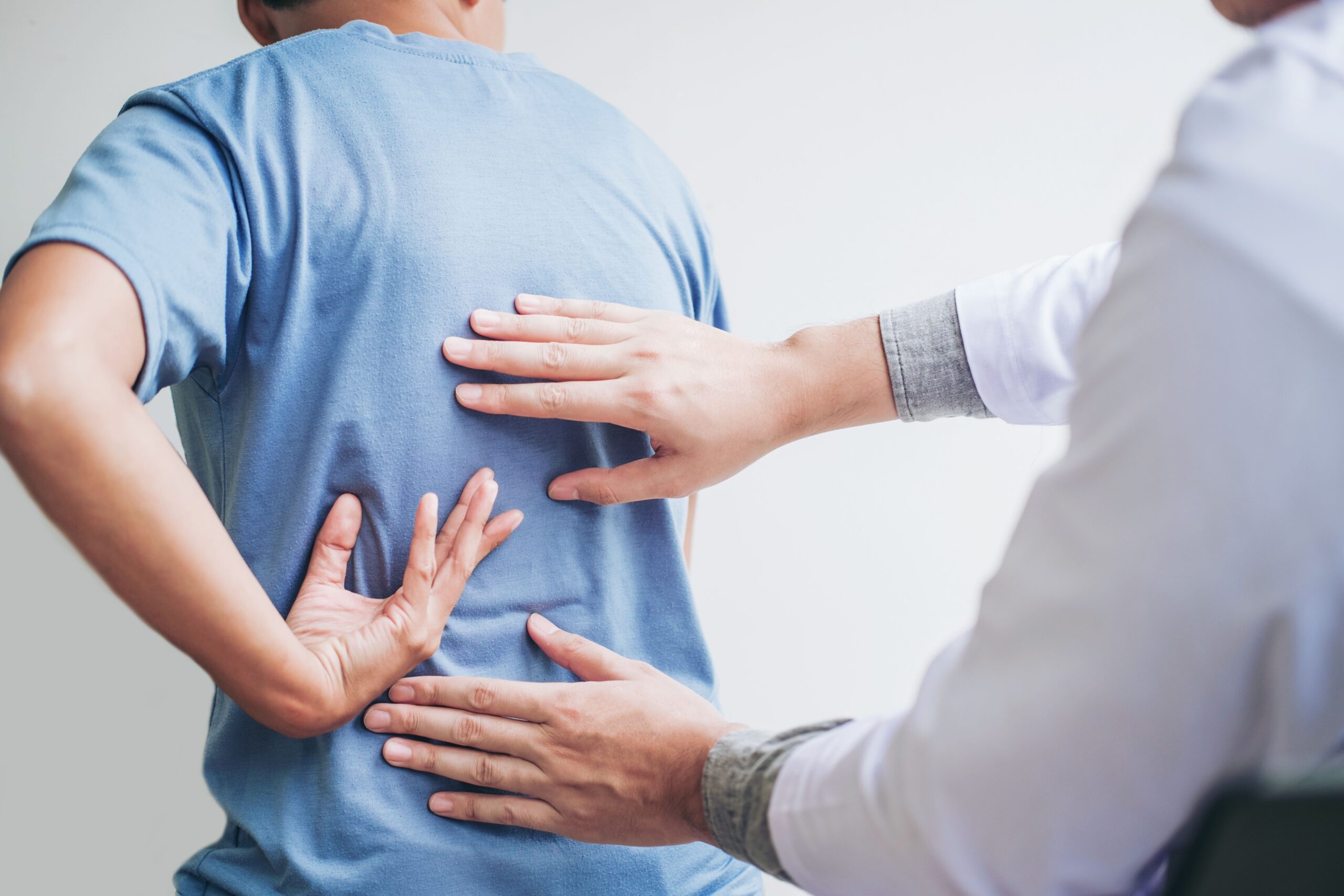 A doctor examining a man's back in a medical office