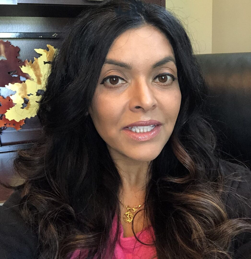 A woman with long black hair wearing a pink shirt.